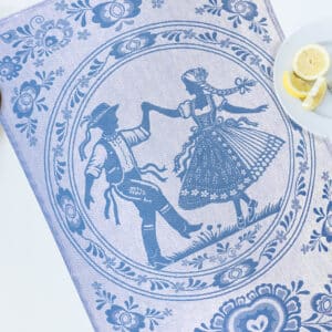 Blue Czech folk tea towel featuring a traditionally dressed dancing couple surrounded by woven floral patterns.