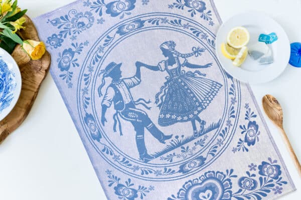 Blue Czech folk tea towel featuring a traditionally dressed dancing couple surrounded by woven floral patterns.